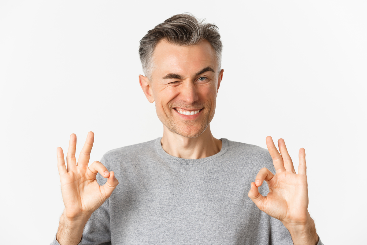 Man giving double okay signs while smiling, representing approval of orthodontic treatment results.