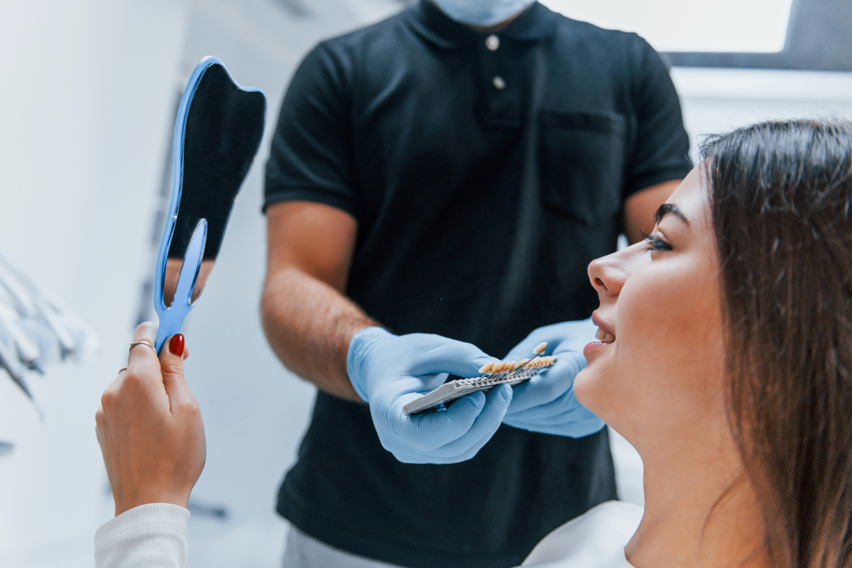 Female patient examines shade guide during orthodontic consultation with dentist in Pompano Beach.